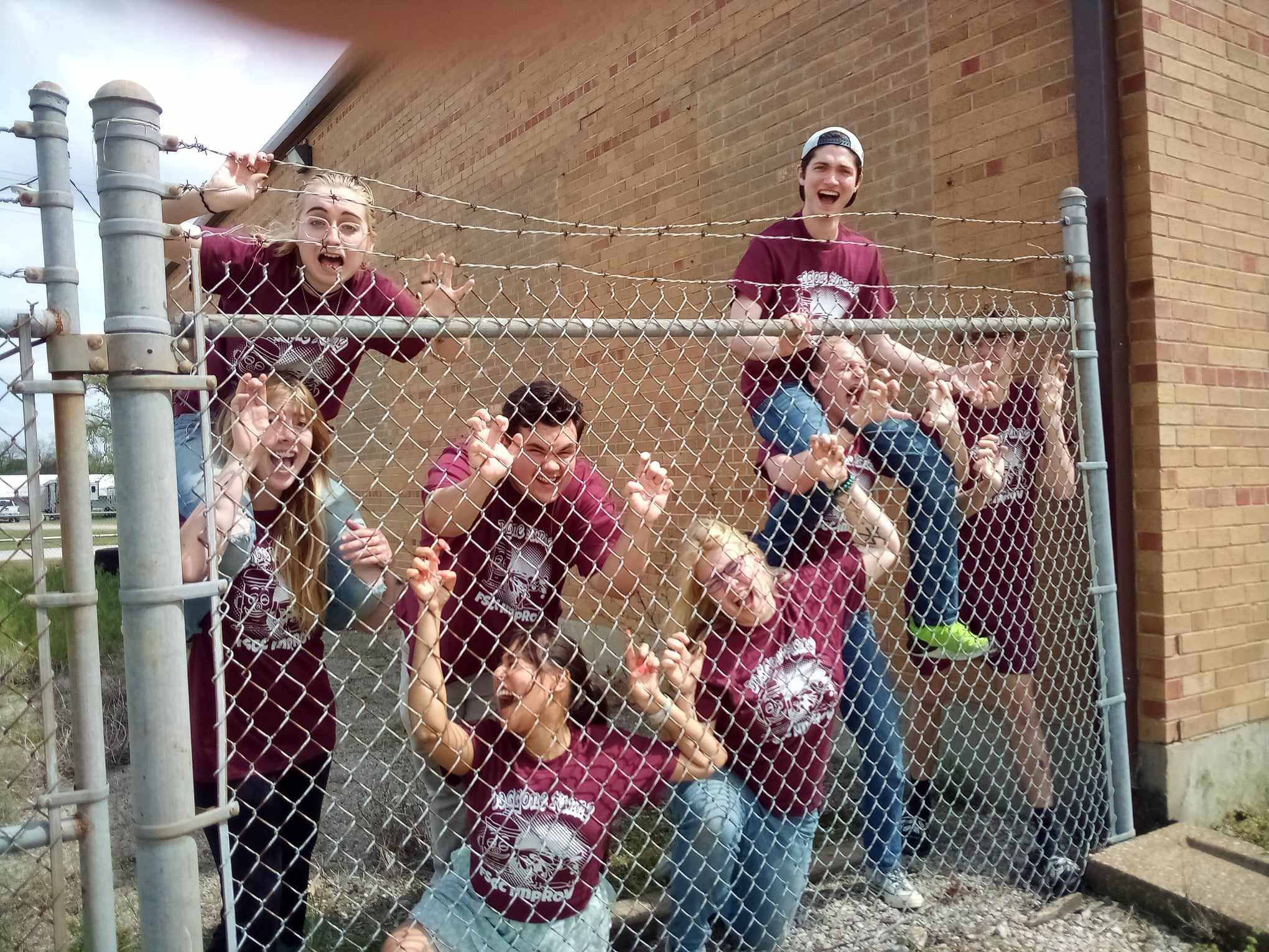 photo of a group of students smashed up against a fence trying to get out looking silly