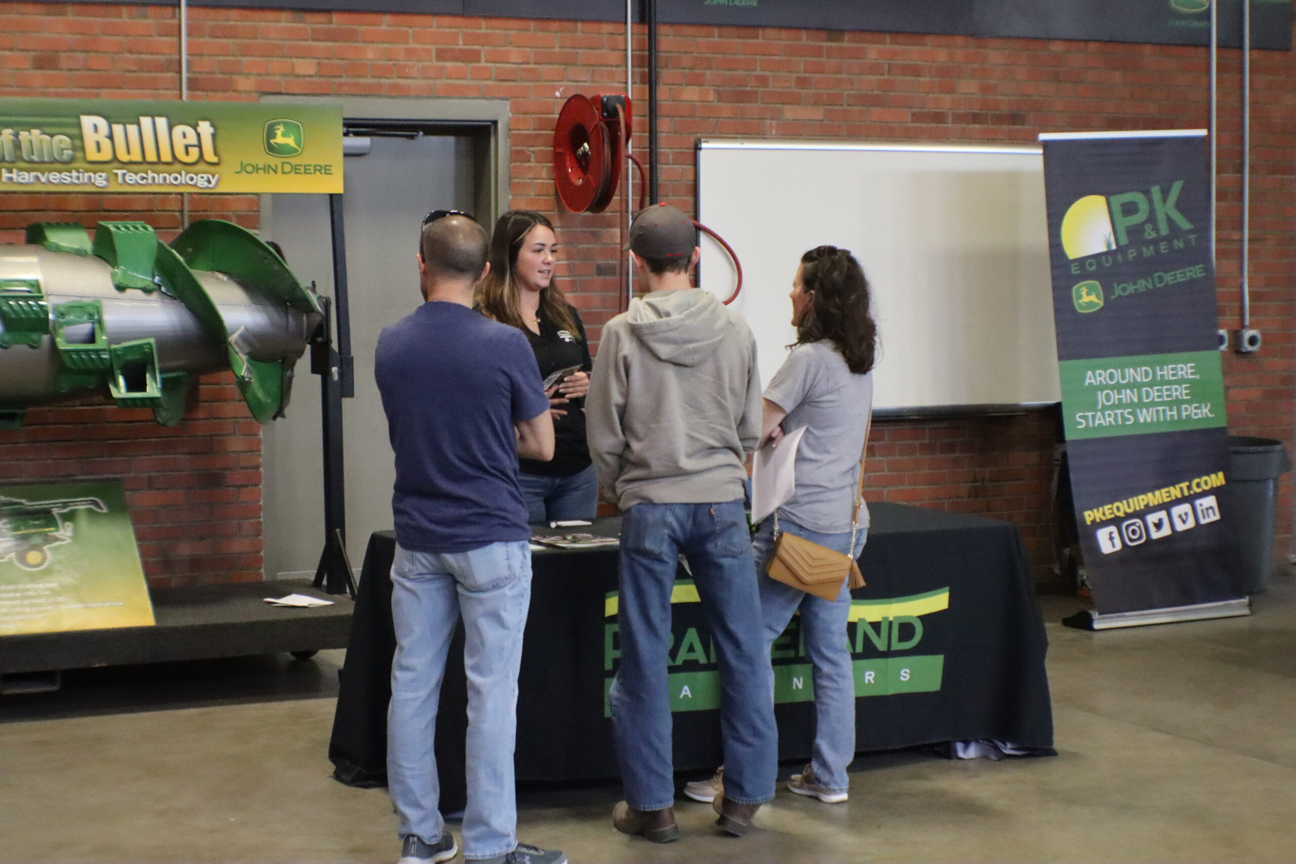 Picture of a vendor at a John Deere Open House talking to parents and a potential future John Deere Technician Training student