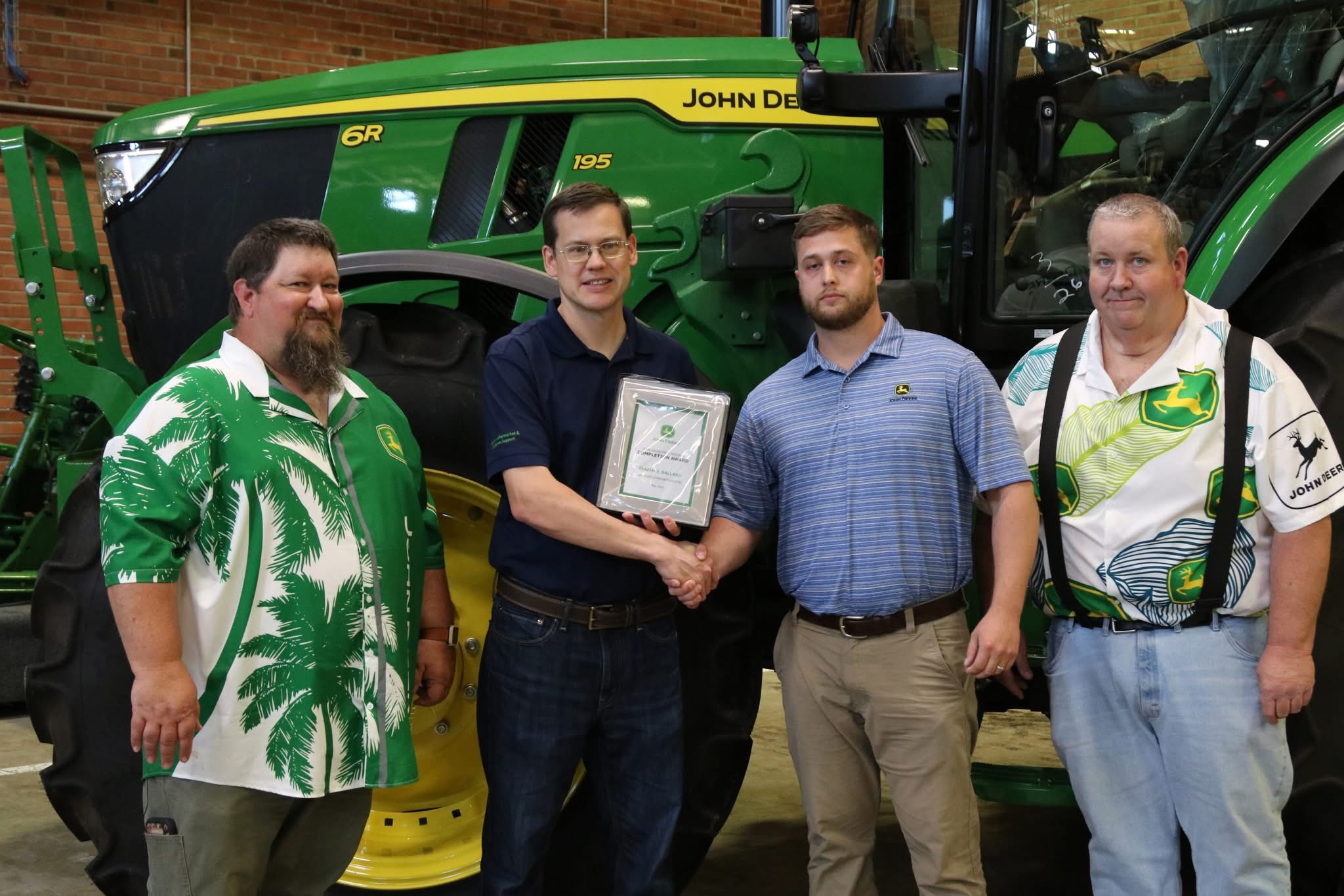 Photo of 4 men standing in front of a tractor